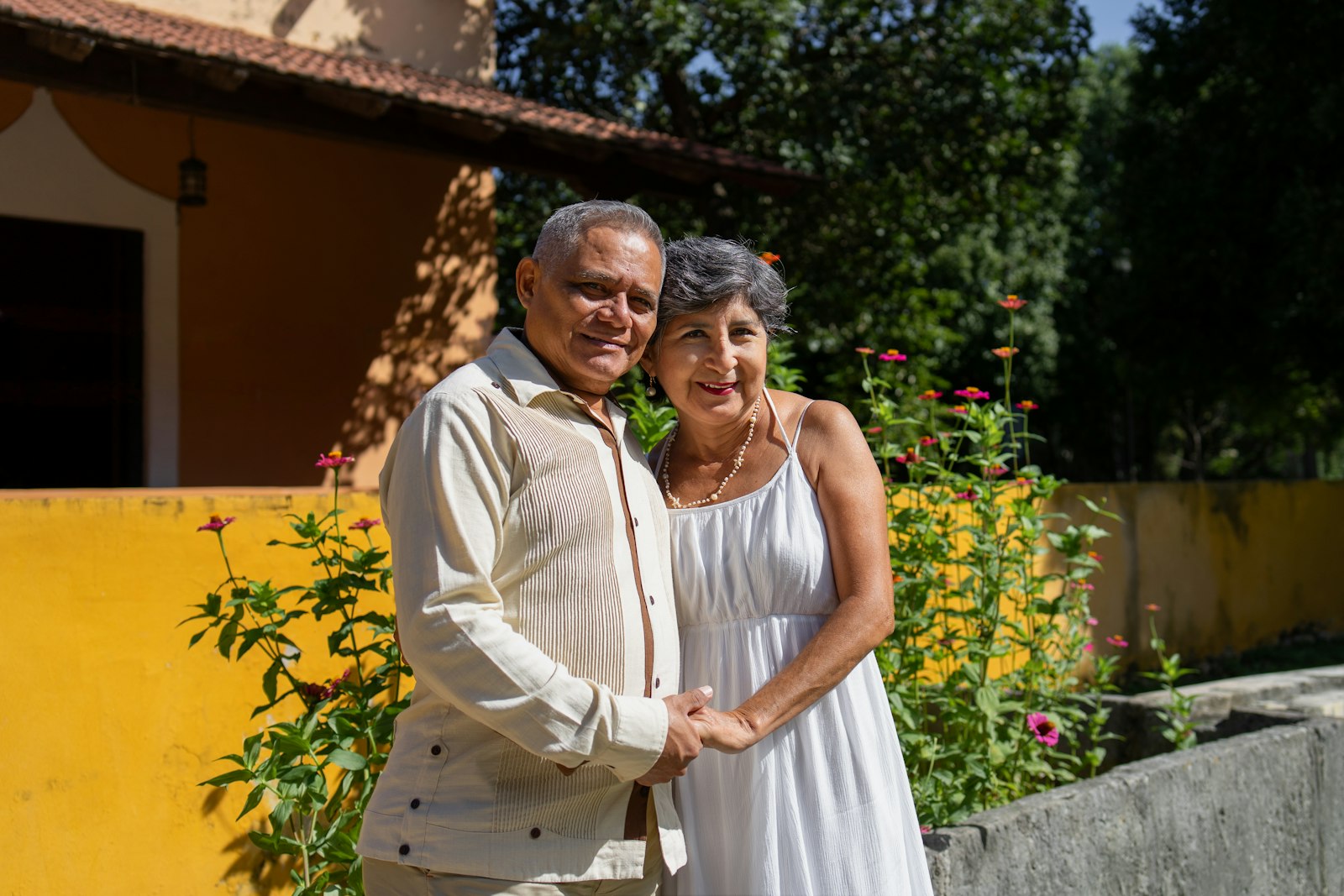 A smiling older couple standing together outside their home